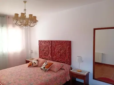 a bedroom with a bed with a red headboard and a mirror at Villa Playa La Barrosa in Novo Sancti Petri