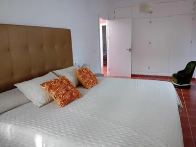 a large white bed with two orange pillows on it at Villa Playa La Barrosa in Novo Sancti Petri