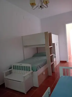 a small bedroom with a bunk bed and a chair at Villa Playa La Barrosa in Novo Sancti Petri