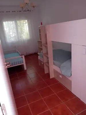 a room with two bunk beds and a red tile floor at Villa Playa La Barrosa in Novo Sancti Petri