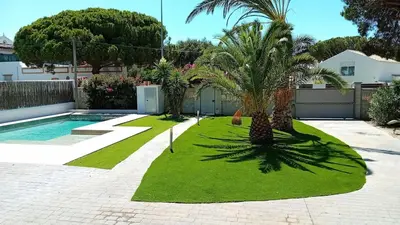 a garden with palm trees and a swimming pool at Villa Playa La Barrosa in Novo Sancti Petri