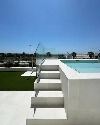 a swimming pool and stairs next to a swimming pool at Penthouse duplex with jacuzzi, 5 min to beach in Chipiona