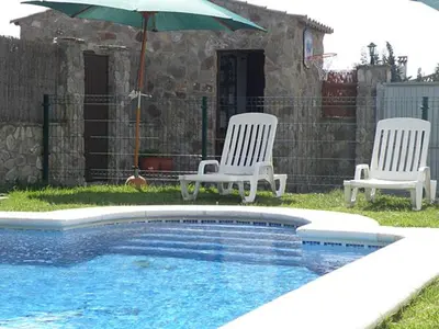 three chairs and an umbrella next to a swimming pool at Casas Elena-Conil in Conil de la Frontera