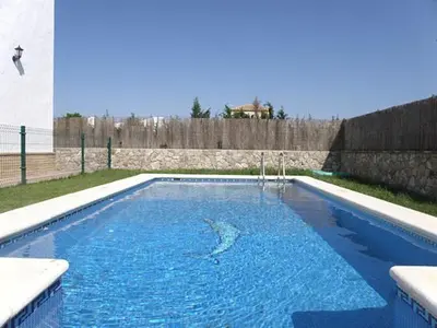 a swimming pool with blue water in a yard at Casas Elena-Conil in Conil de la Frontera