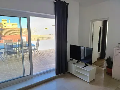 a living room with a tv and a sliding glass door at Ático recién reformado en el centro de Sanlúcar - LOVE SANLUCAR in Sanlúcar de Barrameda