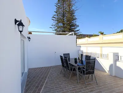 a patio with a table and chairs on a balcony at Ático recién reformado en el centro de Sanlúcar - LOVE SANLUCAR in Sanlúcar de Barrameda
