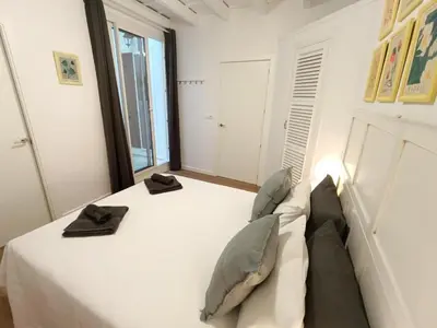 a bedroom with a white bed with two black towels on it at Newly renovated flat in the center of Sanlúcar - EARTH SANLUCAR in Sanlúcar de Barrameda