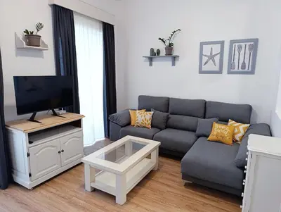 a living room with a couch and a tv at Newly renovated flat in the center of Sanlúcar - EARTH SANLUCAR in Sanlúcar de Barrameda