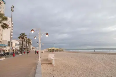 a beach with a row of street lights on it at Victoriamar in Cádiz