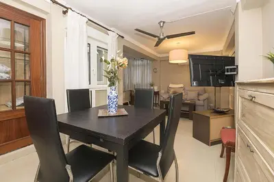 a dining room table with chairs and a vase with flowers at Victoriamar in Cádiz