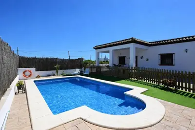 a villa with a swimming pool in front of a house at Chalet Amanecer in Conil de la Frontera