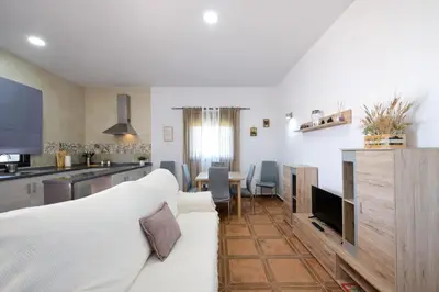 a living room with a white couch and a kitchen at Chalet Atardecer in Conil de la Frontera
