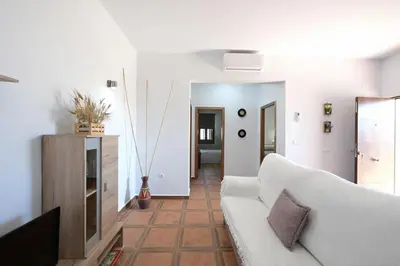 a living room with a white couch and a television at Chalet Atardecer in Conil de la Frontera