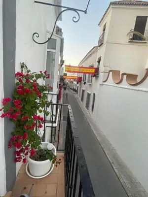 a balcony with pink flowers on a building at Large historic house in the center of Barrio Alto in Sanlúcar de Barrameda