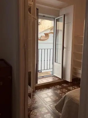 a bedroom with a door open to a balcony at Large historic house in the center of Barrio Alto in Sanlúcar de Barrameda