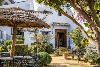 a patio with tables and chairs in front of a white building at Large historic house in the center of Barrio Alto in Sanlúcar de Barrameda