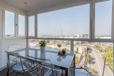 a dining room with a table and chairs and windows at Ático Avda Cádiz Playa in Cádiz