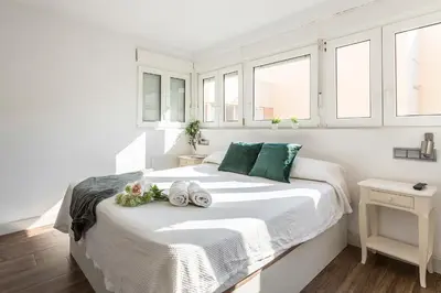 a white bedroom with a bed with towels on it at Ático Avda Cádiz Playa in Cádiz