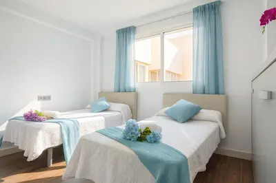 two beds in a room with blue curtains at Ático Avda Cádiz Playa in Cádiz