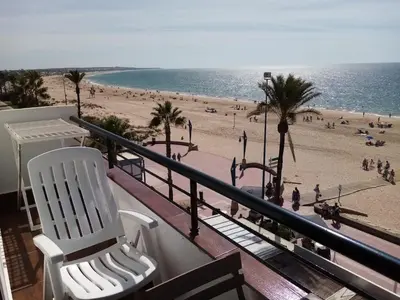 a balcony with two white chairs and a beach at La Barrosa beach Chiclana in Novo Sancti Petri