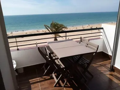 a balcony with a table and a view of the beach at La Barrosa beach Chiclana in Novo Sancti Petri