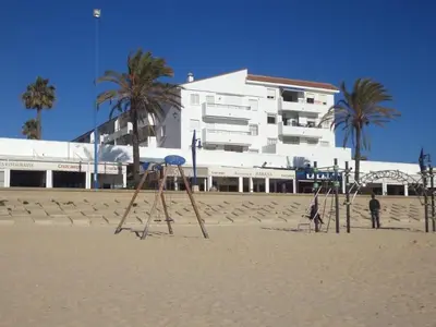two people standing on the beach with swings at La Barrosa beach Chiclana in Novo Sancti Petri