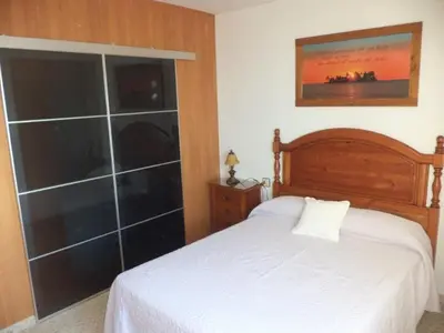 a bedroom with a white bed and a large glass wall at La Barrosa beach Chiclana in Novo Sancti Petri