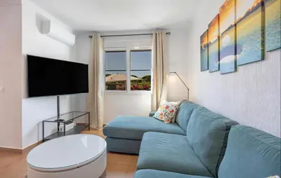 a living room with a blue couch and a tv at Nice Home In Chiclana De La Fronter in Novo Sancti Petri