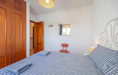 a bedroom with a bed with blue and white stripes at Nice Home In Chiclana De La Fronter in Novo Sancti Petri