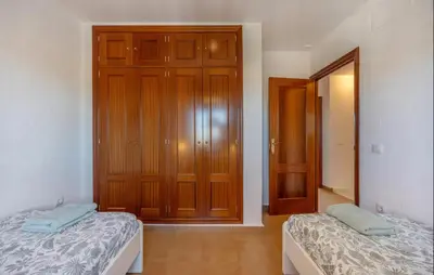 a bedroom with two beds and a wooden closet at Nice Home In Chiclana De La Fronter in Novo Sancti Petri