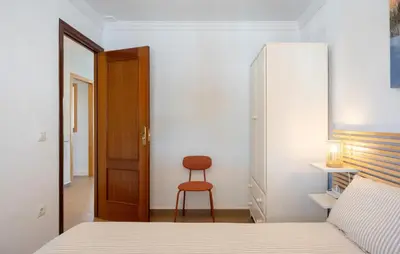 a bedroom with a bed and a chair and a closet at Nice Home In Chiclana De La Fronter in Novo Sancti Petri