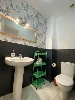 a bathroom with a sink and a toilet and a mirror at Dúplex Casco Histórico, terraza, garaje in Sanlúcar de Barrameda