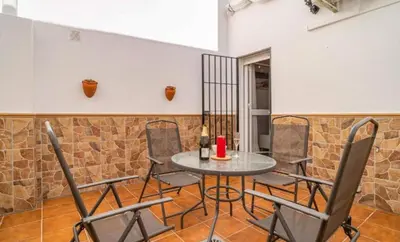 a table and chairs in a room with a stone wall at Mi retiro in Chipiona