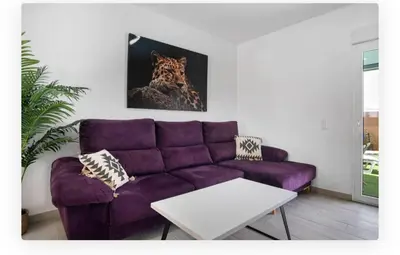 a purple couch in a living room with a painting at Casa Dana in Cádiz