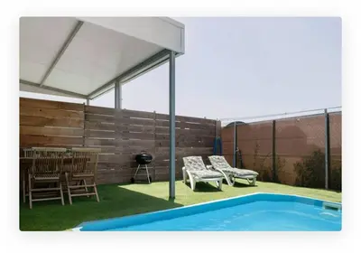 a covered patio with chairs and a swimming pool at Casa Dana in Cádiz