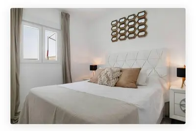 a white bedroom with a large bed and a window at Casa Dana in Cádiz