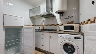 a kitchen with a washing machine and a microwave at La Caleta Prime Grupo AC Gestion in Cádiz
