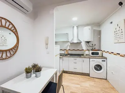a white kitchen with a table and a washing machine at La Caleta Prime Grupo AC Gestion in Cádiz