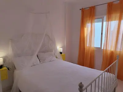 a bedroom with a white bed and a window at La Buganvilla, bright and spacious apartment in the city centre in Chipiona