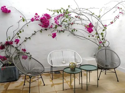 two chairs and a table with pink flowers on a wall at La Buganvilla, bright and spacious apartment in the city centre in Chipiona