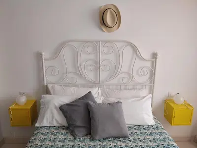a white bed with two pillows and a clock on the wall at La Buganvilla, bright and spacious apartment in the city centre in Chipiona