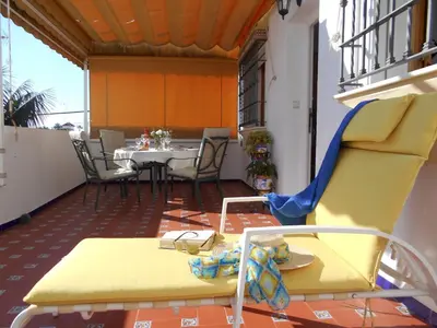 a yellow chair on a balcony with a table at Apartment Penthouse- Klimatisierung- Strand und Sonne das ganze Jahr über by Interhome in Chipiona
