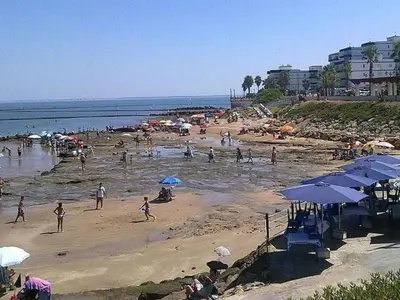 a group of people on a beach with umbrellas at Holiday Home Touristenwohnung Apartment mit Terrasse by Interhome in Chipiona
