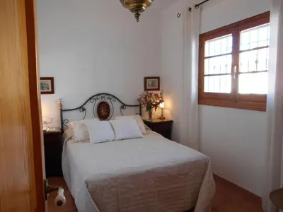 a bedroom with a bed with white sheets and a window at Apartment Wohnung Klimaanlage- Wifi- Terrasse- by Interhome in Chipiona