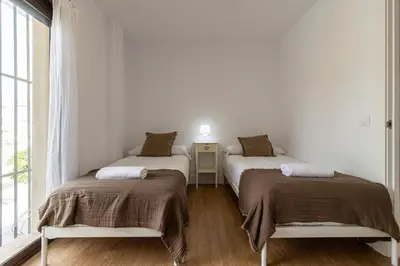two beds in a white room with a window at Allo Apartments Catedral Centro 3 Habitaciones in Jerez de la Frontera