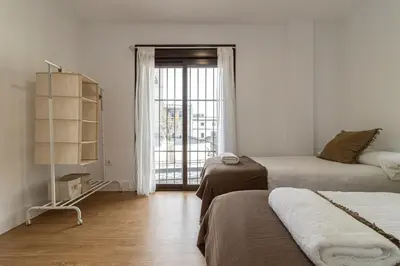 a bedroom with two beds and a large window at Allo Apartments Catedral Centro 3 Habitaciones in Jerez de la Frontera