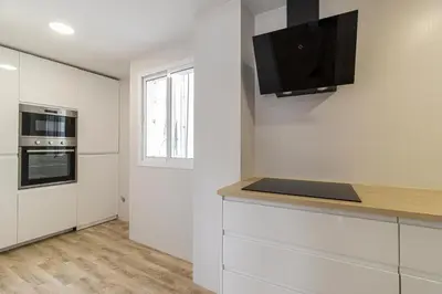a kitchen with white cabinets and a tv on the wall at Allo Apartments Catedral Centro 3 Habitaciones in Jerez de la Frontera