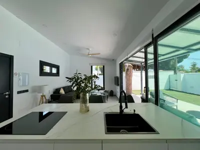 a kitchen with a sink and a living room at Casa Lumier in Chiclana de la Frontera