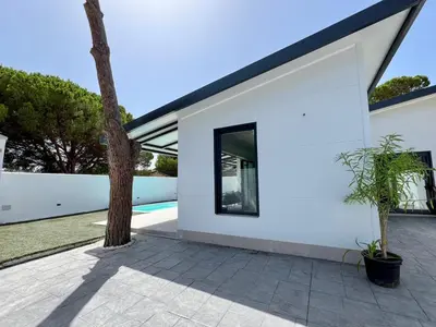 a white house with a tree in the courtyard at Casa Lumier in Chiclana de la Frontera