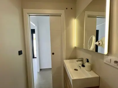 a white bathroom with a sink and a mirror at Casa Lumier in Chiclana de la Frontera